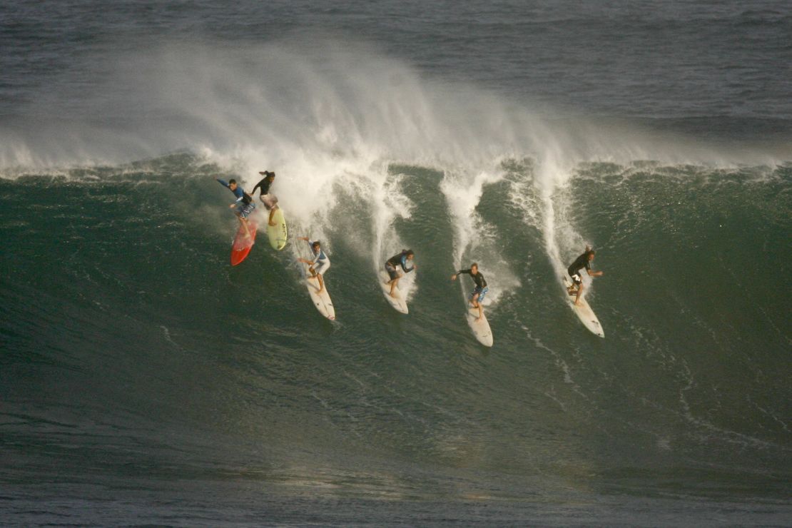 Six surfers drop into a wave during pre-contest surfing at the Eddie Aikau Big-Wave Invitational in 2009.