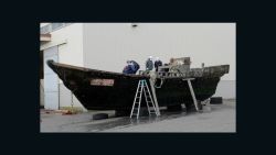 This picture taken on November 24, 2015 shows coast guard officials investigating a wooden boat at the Fukui port in Sakai city in Fukui prefecture, western Japan after the ship was found drifting off the coast of Fukui. Japan is investigating nearly a dozen suspicious boats recently found drifting off the country's coastline, some with decaying bodies aboard, officials said on November 27, as media speculated they came from North Korea. At least 11 cases involving wooden boats -- some badly damaged -- with 20 bodies on board have been reported during October and November.