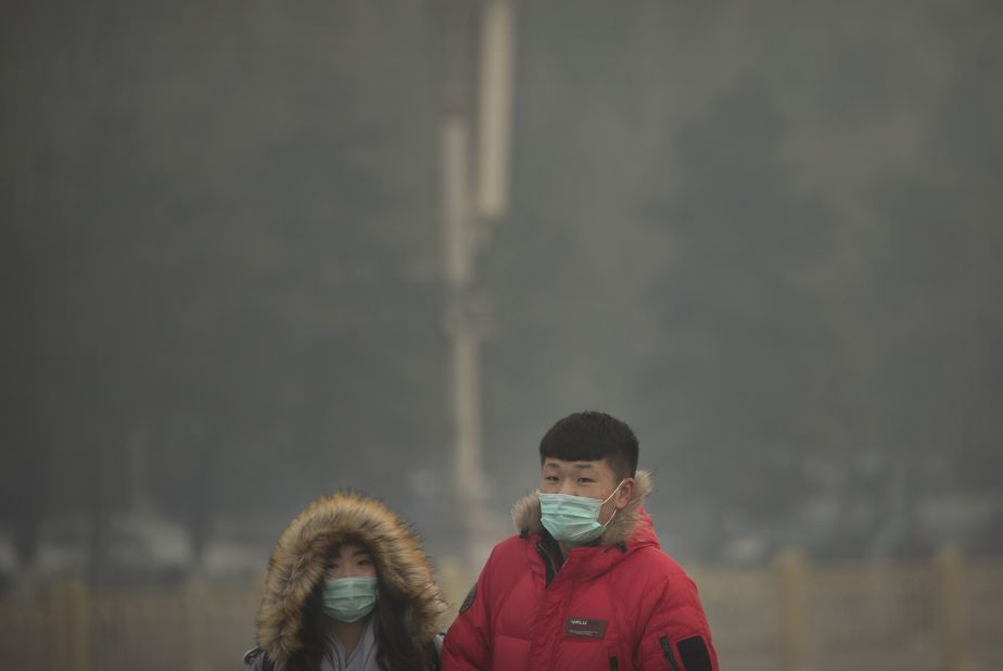 People wearing face masks walk across Tiananmen Square in Beijing on November 28. 