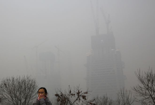 A woman protects herself from pollutants with a piece of cloth as she walks past a construction site on November 30 in Beijing.