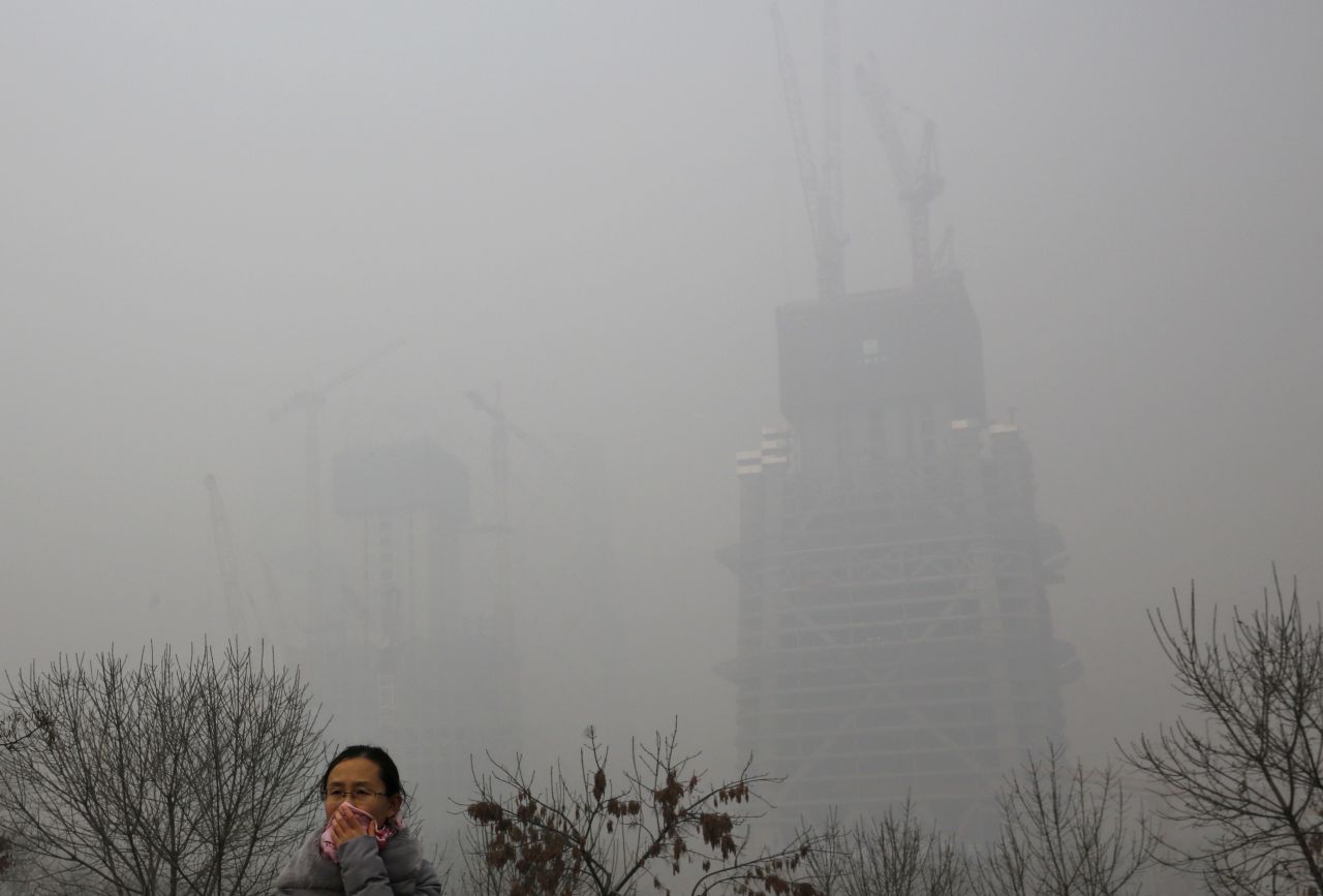 A woman protects herself from pollutants with a piece of cloth as she walks past a construction site on November 30 in Beijing.