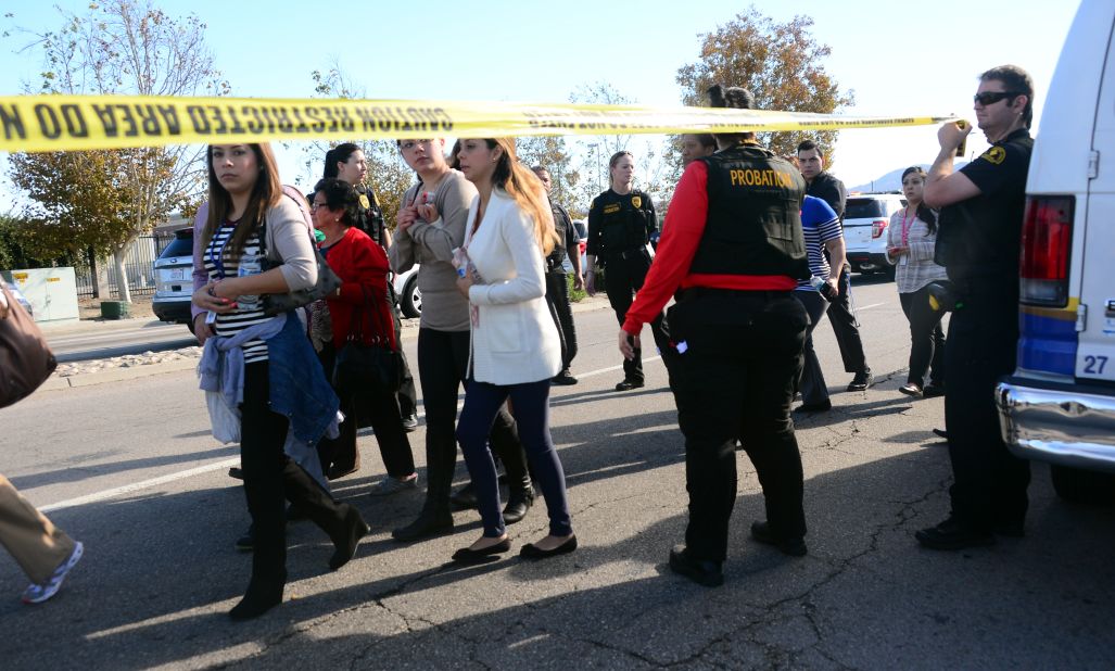 Police escort civilians away from the site of the shooting.