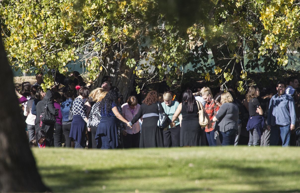 People pray on the San Bernardino Golf Course, across the street from where the shooting took place.