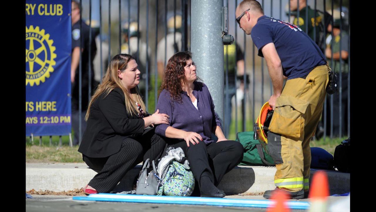 Two women speak with a firefighter at a triage area near the scene.