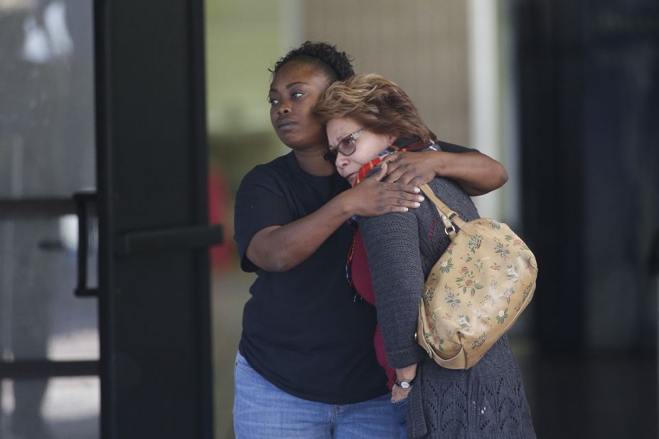 Two women embrace at a community center where family members were gathering to pick up people from the scene.