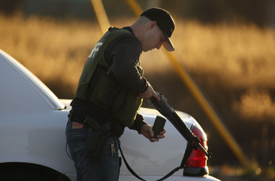 A police officer loads his weapon while pursuing suspects.