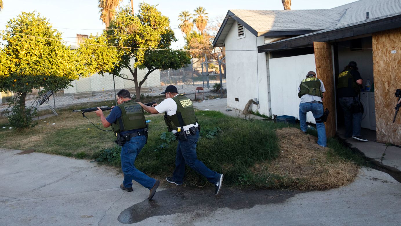 Law enforcement officers search a residential area for suspects who fled after the shooting.