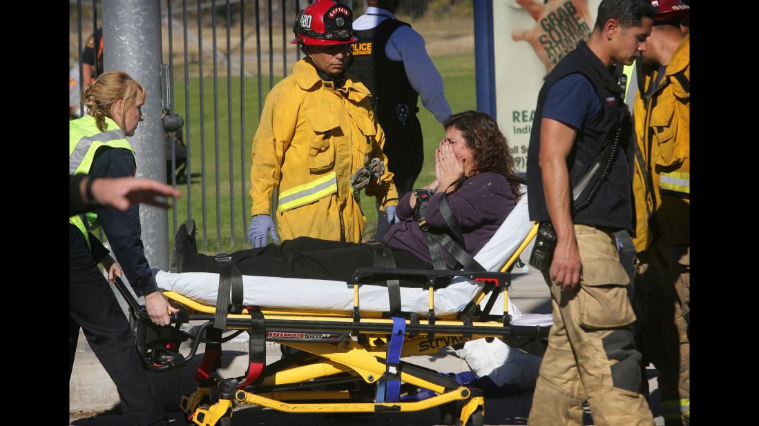 A woman is wheeled away on a stretcher.