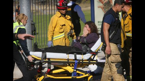 A woman is wheeled away on a stretcher.