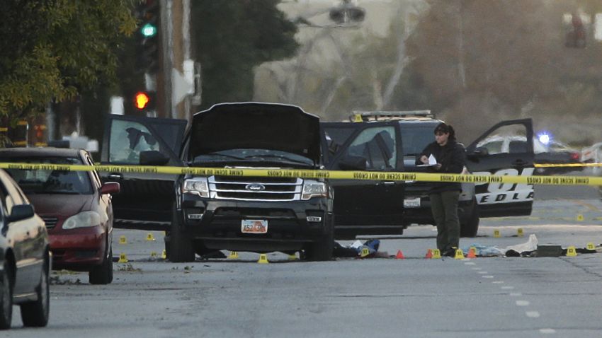 An investigator looks at a Black SUV that was involved in a police shootout with suspects, Thursday, Dec. 3, 2015, in San Bernardino, Calif.  A heavily armed man and woman opened fire Wednesday on a holiday banquet, killing multiple people and seriously wounding others in a precision assault, authorities said. Hours later, they died in a shootout with police.  (AP Photo/Jae C. Hong)