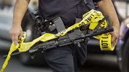 A police officer deploys tape to an area near where authorities stopped a vehicle in San Bernardino, Calif., Wednesday, Dec. 2, 2015. Multiple attackers opened fire on a banquet at a social services center for the disabled in San Bernardino on Wednesday, killing multiple people and sending police on a manhunt for suspects. (AP Photo/Damian Dovarganes)