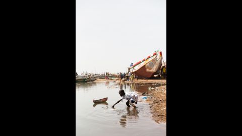 A young boy plays with a homemade toy boat. Like many boys in Guet Ndar, he began playing with boats as a child and will begin fishing before his childhood is over. "I was 9 when I began fishing," said fishing boat captain Baye Sarr. "Back then, Guet Ndar was different. According to the scientists, the sea level rises, but here we have a specific situation: every year, there is a period during which the sea rises and comes closer to the housing area. That time is called 'Lock.' Following the end of that period, the sea withdraws back and people call that time 'Ndey.' "