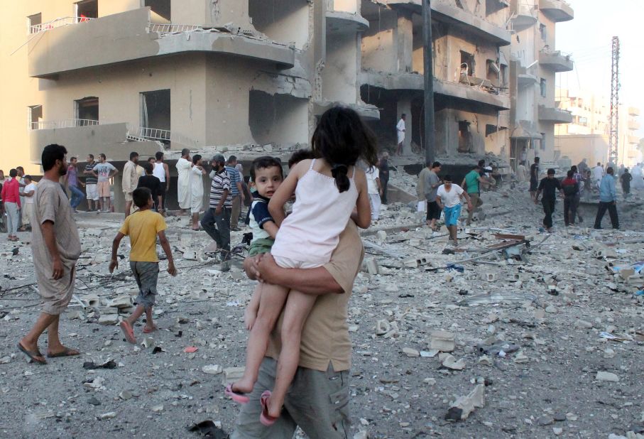 A man carries two children away from the scene of an explosion in Raqqa on August 7, 2013. 
