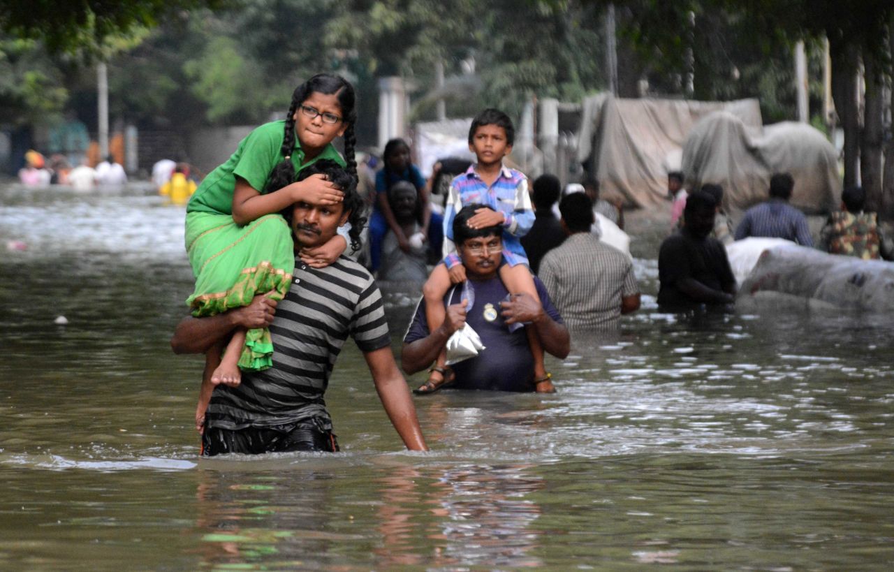 Indian residents carry children as they walk through flood waters in Chennai on December 3.