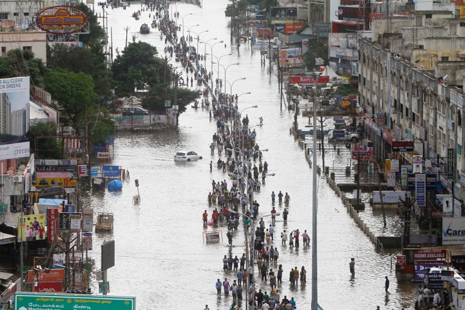 People walk through a flooded street in Chennai, India, Thursday, December 3, 2015. Heaviest rainfalls in more than 100 years have devastated swathes of the southern Indian state of Tamil Nadu, with thousands forced to leave their submerged homes and schools, offices.