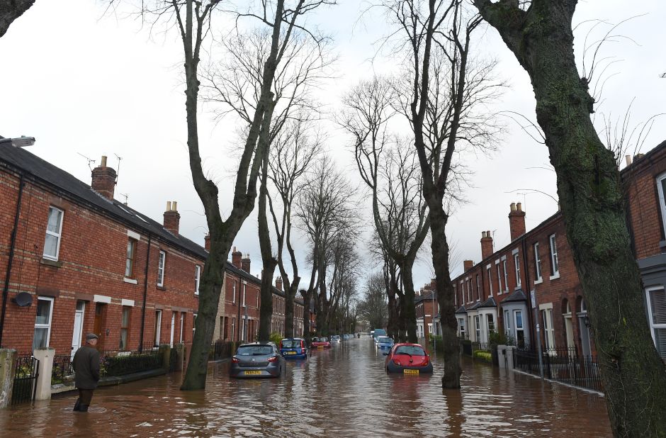 A man walks down a flooded street in Carlisle, England on December 6.