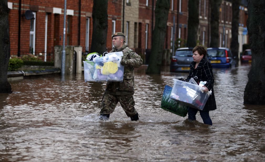 A member of the armed forces helps a resident move their belongings through the flood water in Carlisle, December 6. 