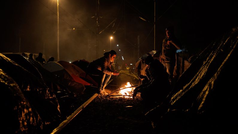 Migrants warm themselves around a fire at the border.