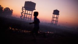 BHOPAL, INDIA - NOVEMBER 27:  A children plays near water towers in front of their homes near the Union Carbide factory on November 27, 2009 in Bhopal, India. Twenty-five years after an explosion causing a mass gas leak, in the Union Carbide factory in Bhopal, killed at least eight thousand people, toxic material from the biggest industrial disaster in history continues to affect Bhopalis. A new generation is growing up sick, disabled and struggling for justice. The effects of the disaster on the health of generations to come, both through genetics, transferred from gas victims to their children and through the ongoing severe contamination, caused by the Union Carbide factory, has only started to develop visible forms recently.  Annan suffers from cerebral palsy and receives vital rehabilitative support and care at the Chingari Trust Rehabilitation Clinic.  (Photo by Daniel Berehulak/Getty Images)