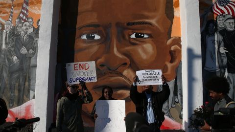BALTIMORE, MD - DECEMBER 08: People hold up signs as Democratic presidential candidate Sen. Bernie Sanders, (I-VT) (L) is given a tour of the Sandtown-Winchester Neighborhood where Freddie Gray lived and was arrested, December 8, 2015 in Baltimore, Maryland. Sen. Sanders later met with African-American religious and civic leaders. (Photo by Mark Wilson/Getty Images)