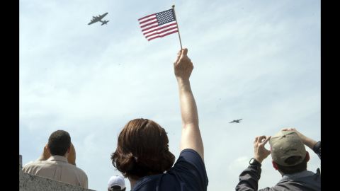 A spectator waves to World War II-era aircraft as they fly over the National World War II Memorial in Washington on Friday, May 8. The flyover commemorated the 70th anniversary of V-E Day.