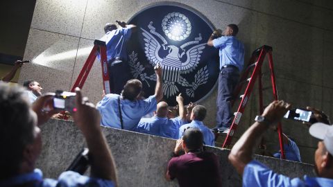 U.S. Embassy employees in Havana, Cuba, hang the seal of the United States a few hours before its ceremonial flag-raising on Friday, August 14. Cuba and the United States re-established diplomatic relations in July.