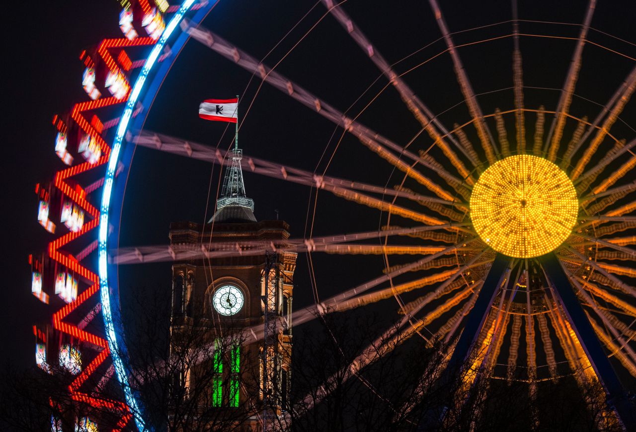 Berlin's town hall is seen through a revolving Ferris wheel at a Christmas market.