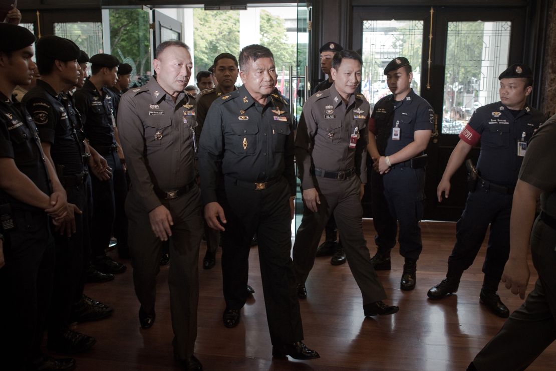 Thai Army Lt. Gen. Manas Kongpan, center, is surrounded by police as he turns himself in at police headquarters in Bangkok on June 3, 2015.