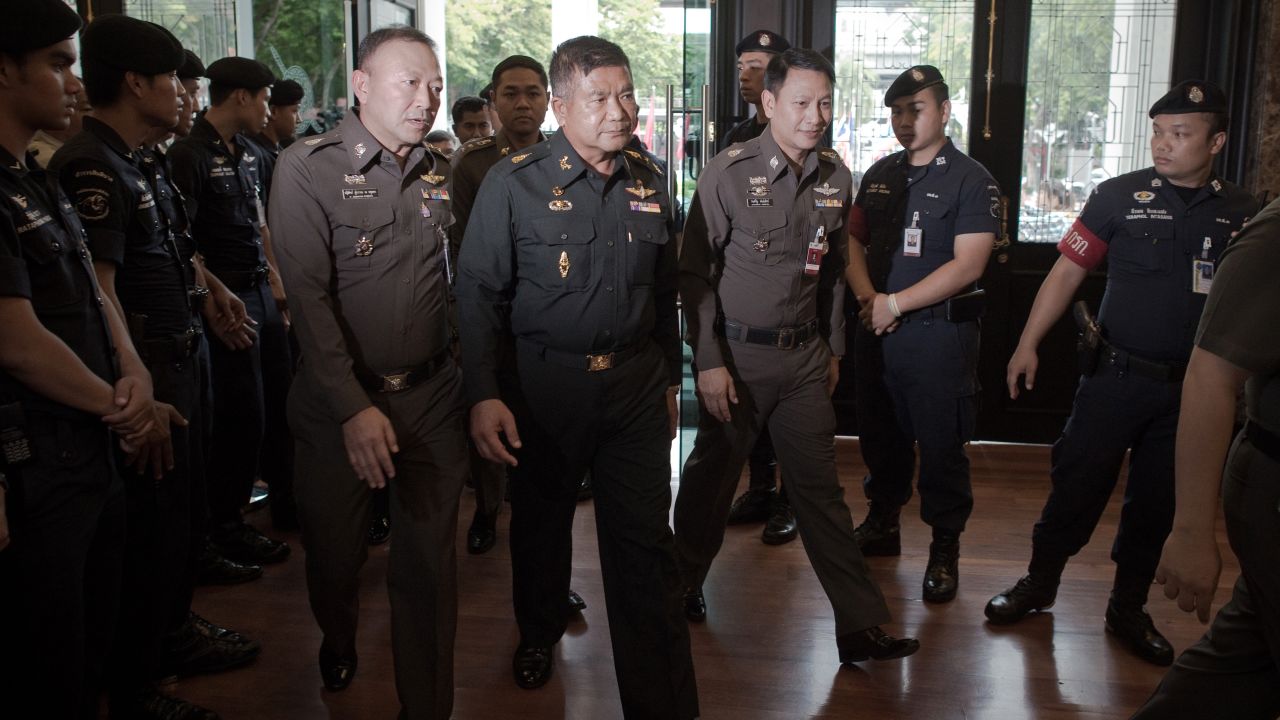 Thai Army Lt. Gen. Manas Kongpan, center, is surrounded by police as he turns himself in at police headquarters in Bangkok on June 3, 2015.