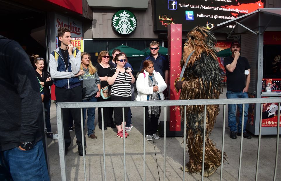 Bystanders watch as a person dressed in a Chewbacca costume walks near where fans have been congregating at the plaza in front of the TCL Theatre.