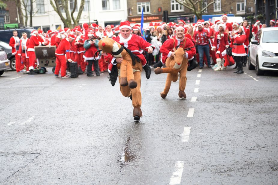 Two participants in Santa and reindeer costumes race each other during a SantaCon event in London, England.