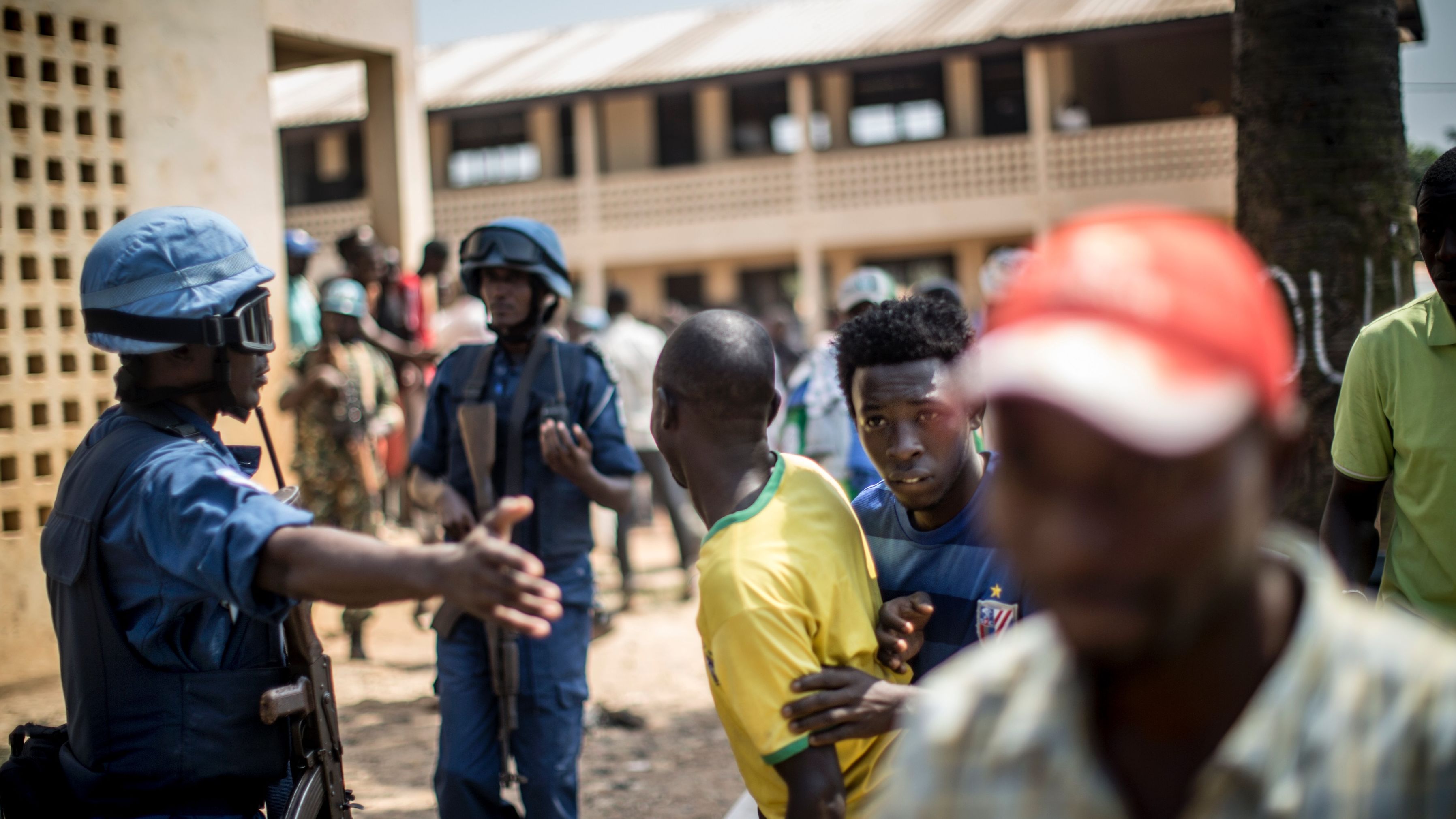 Soldiers direct Burundi civilians to cover as gunfire is directed toward a school where voters were gathered in December.

