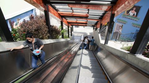 TO GO WITH AFP STORY by Ariela Navarro
People use the covered outdoor escalators at Comuna 13, one of the poorest neighbourhoods of Medellin, Antioquia department, Colombia, on January 5, 2014. The system transformed the mobility of local people, replacing more than 350 concrete steps. The escalators are divided in six sections and benefit 12 thousand users. In 2013 Medellin was chosen by popular vote through the internet as the Innovative City of the Year during the City of the Year contest, organized by The Wall Street Journal and Citigroup. The distinction was basically made for its modern transportation system, its public library, escalators built in this shantytown and schools that have allowed the integration of society.   AFP PHOTO/Fredy AMARILES        (Photo credit should read FREDY AMARILES GARCIA/AFP/Getty Images)