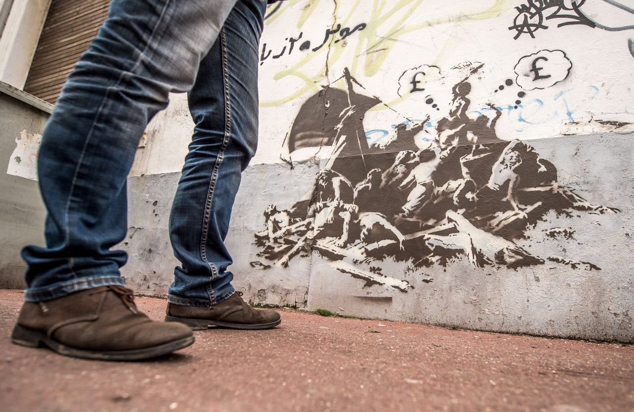A man stands next to Banksy's latest work, in Calais, France.