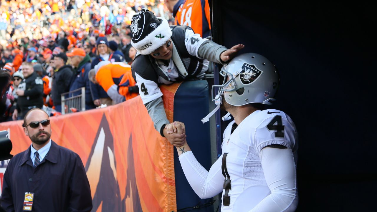 A fan reaches out to Oakland quarterback Derek Carr before an NFL game in Denver on Sunday, December 13.