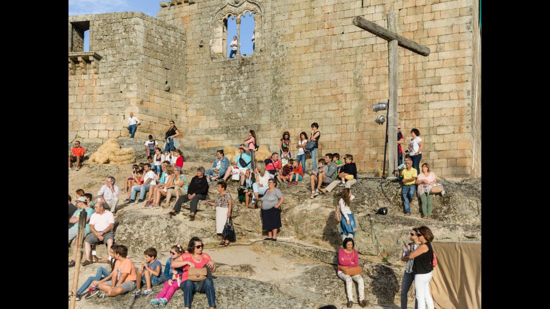 People sunbathe on the rocks that form the base of a castle in Belmonte, Portugal.