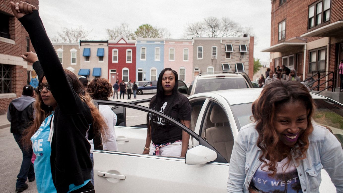 Women dance in front of their cars during the recording of a music video in memory of Freddie Gray.