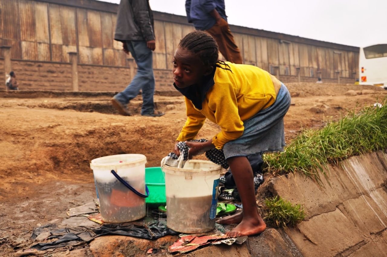 Many of the photos taken by the children reflect the harsh environment they are forced to live in.  Hygiene is poor and raw sewage is often present in the streets<br />Here, a young girl does her laundry by the side of the road.  