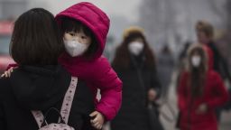 A Chinese girl wears a mask to protect against pollution as she is carried in a shopping district in heavy smog on December 8, 2015 in Beijing, China.