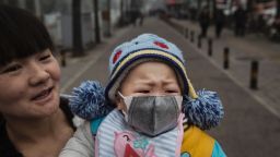BEIJING, CHINA - DECEMBER 08:  A Chinese girl wears a mask as she is held by her mother outside a local hospital during a day of heavy smog on December 8, 2015 in Beijing, China. The Beijing government issued a "red alert" for the first time since new standards were introduced earlier this year as the city and many parts of northern China were shrouded in heavy pollution. Levels of PM 2.5, considered the most hazardous, crossed 400 units in Beijing, lower than last week, but still nearly 20 times the acceptable standard set by the World Health Organization. The governments of more than 190 countries are meeting in Paris to set targets on reducing carbon emissions in an attempt to forge a new global agreement on climate change.  (Photo by Kevin Frayer/Getty Images)