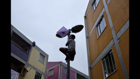 A child tries to retrieve his kite snagged on a lamppost in the Rocinha favela. "Kites are playful; they are meant to soar in the air," Bastianelli said. "This one was tangled, much like the favela's residents continue to be in Rio's ongoing 'war on drugs' between the police and the gangs."