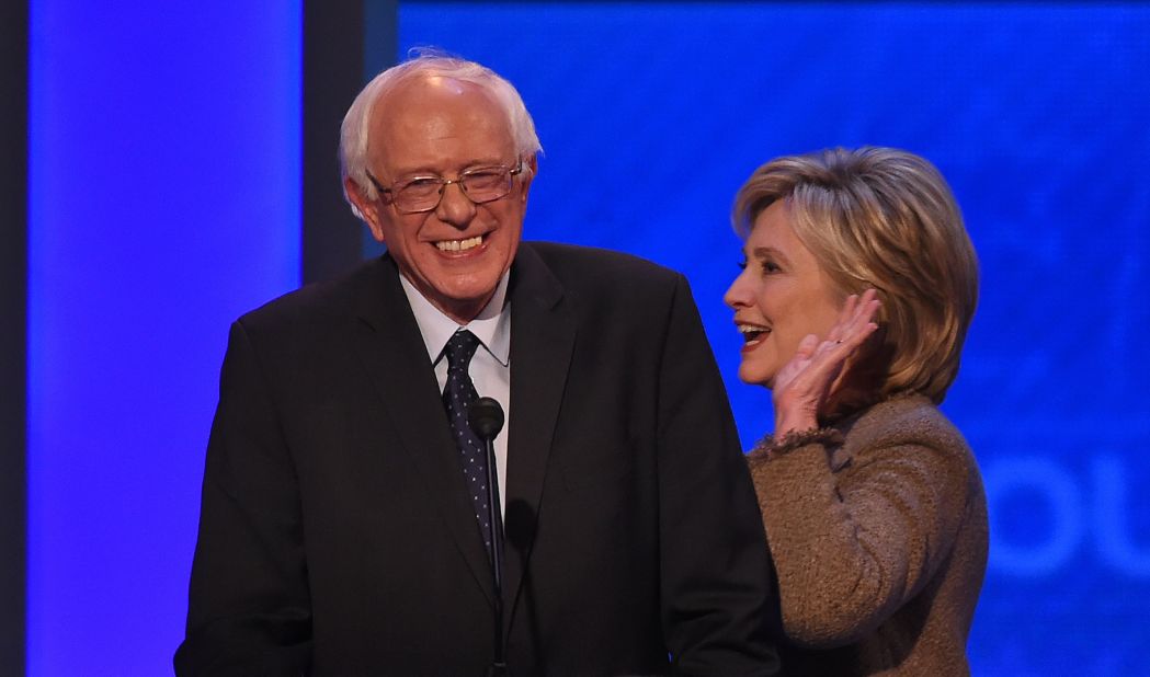 Clinton smiles as she walks past Sanders during a commercial break at the Democratic debate held in Manchester, New Hampshire, on Saturday, December 19. 