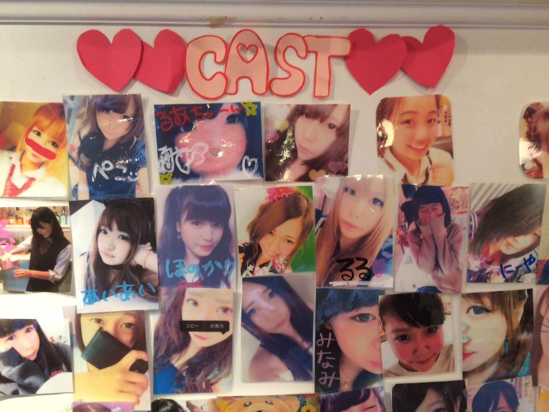 A wall showing photos of young women in a Japanese schoolgirl cafe.