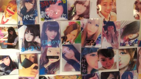 A wall showing photos of young women in a Japanese schoolgirl cafe.