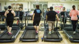 People walk on treadmills in a gymnasium.