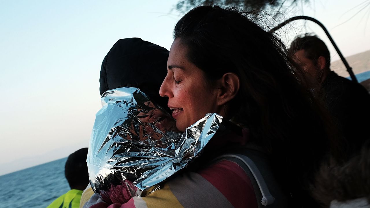 SIKAMINIAS, GREECE - OCTOBER 17:  A mother and child rejoice after arriving on a raft moments before from Turkey onto the island of Lesbos on October 17, 2015 in Sikaminias, Greece. Dozens of rafts and boats are still making the journey daily as thousands flee conflict in Iraq, Syria, Afghanistan and other countries. More than 500,000 migrants have entered Europe so far this year. Of that number four-fifths of have paid to be smuggled by sea to Greece from Turkey, the main transit route into the EU. Nearly all of those entering Greece on a boat from Turkey are from the war zones of Syria, Iraq and Afghanistan.  (Photo by Spencer Platt/Getty Images)