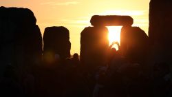 AMESBURY, ENGLAND - DECEMBER 21:  A man takes a photograph of the sunrise as druids, pagans and revellers celebrate the winter solstice at Stonehenge on December 21, 2012 in Wiltshire, England. Predictions that the world will end today as it marks the end of a 5,125-year-long cycle in the ancient Maya calendar, encouraged a larger than normal crowd to gather at the famous historic stone circle to celebrate the sunrise closest to the Winter Solstice, the shortest day of the year.  (Photo by Matt Cardy/Getty Images)
