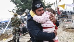 A man carrying a baby cries after crossing the Greek-Macedonian border with other migrants and refugees, near the town of Gevgelija, on December 4, 2015.
