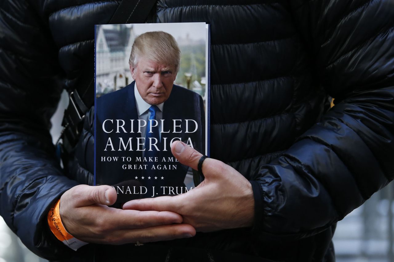 A man holds a copy of Trump's newest book, "Crippled America: How to Make America Great Again," while he waits to have it signed by Trump outside Trump Tower in New York on November 3.