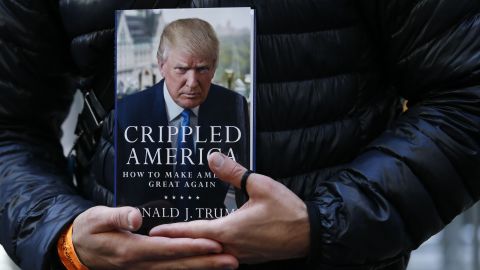 A man holds a copy of Trump's newest book, "Crippled America: How to Make America Great Again," while he waits to have it signed by Trump outside Trump Tower in New York on November 3.